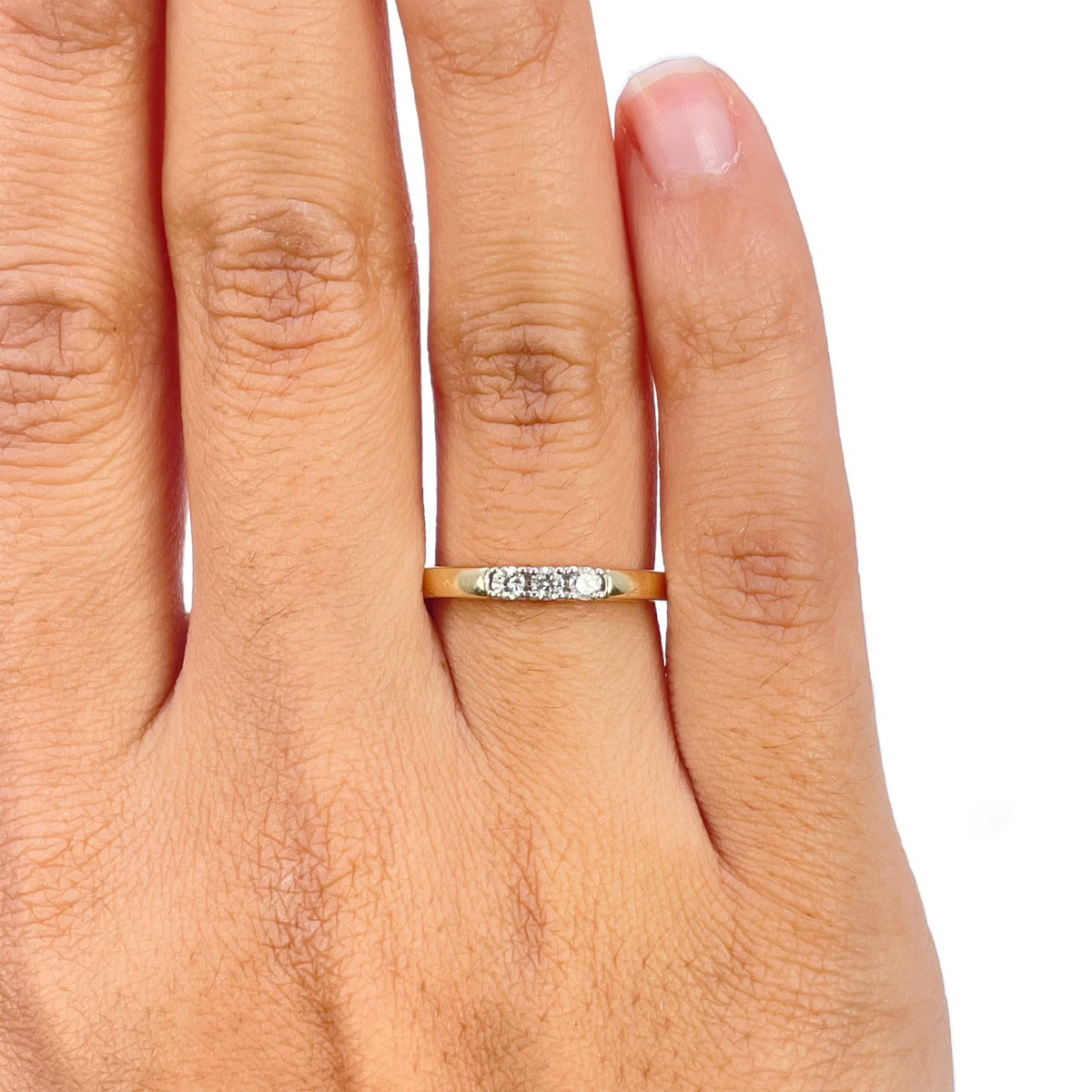 Close-up of three round diamonds in white gold claws on 18ct yellow gold trilogy ring
